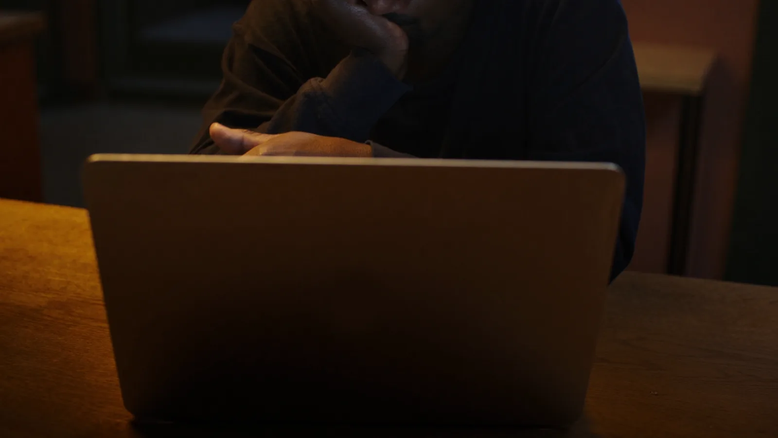 Persona esitante davanti al portatile, con la mano sospesa sulla tastiera